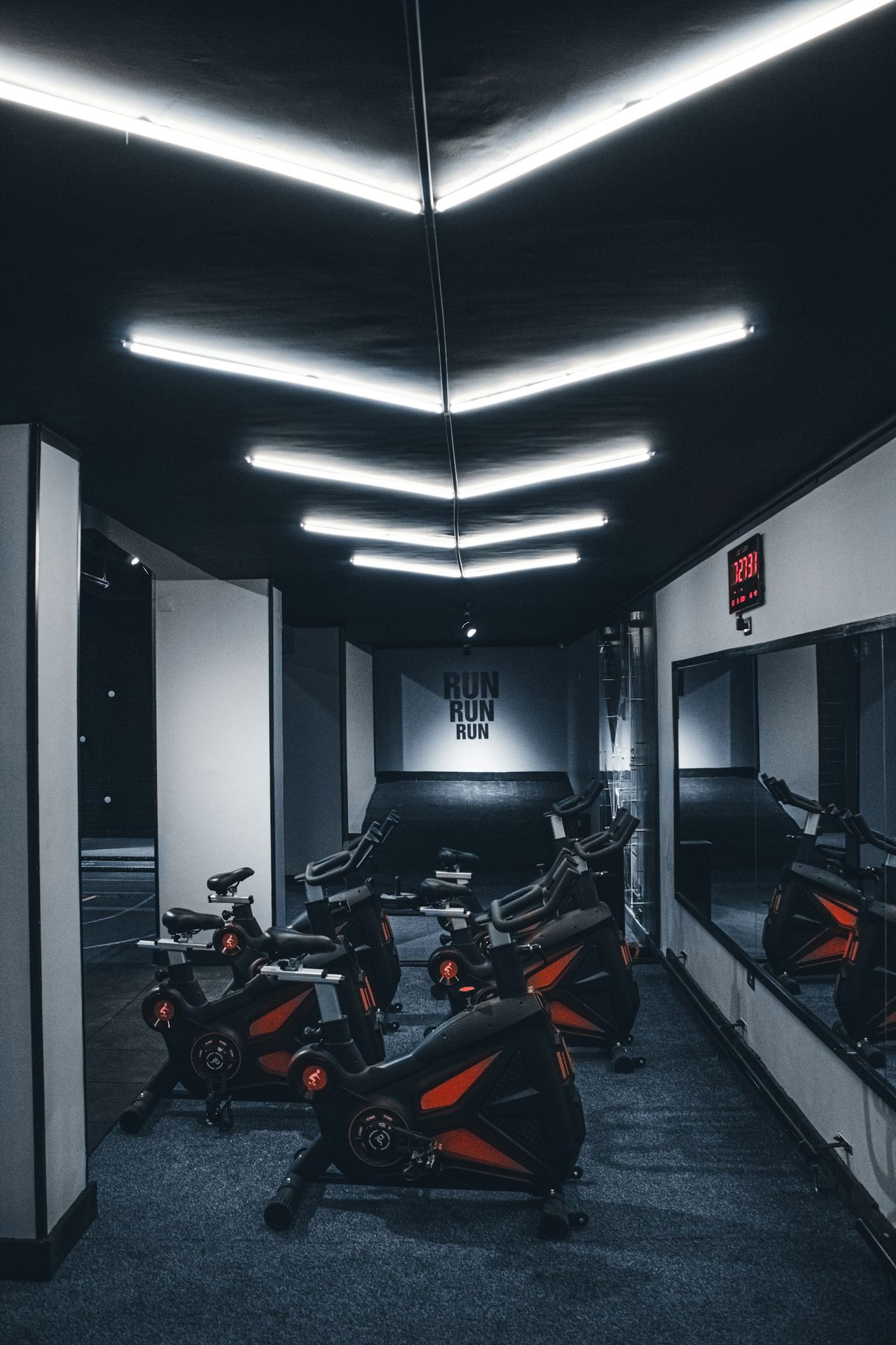 a gym with a row of stationary exercise bikes